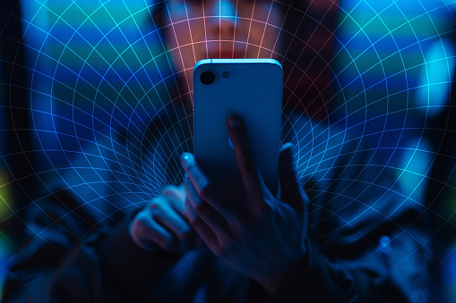 A person holding a smartphone in front of their face, overlaid with a digital blue and orange radial grid pattern.