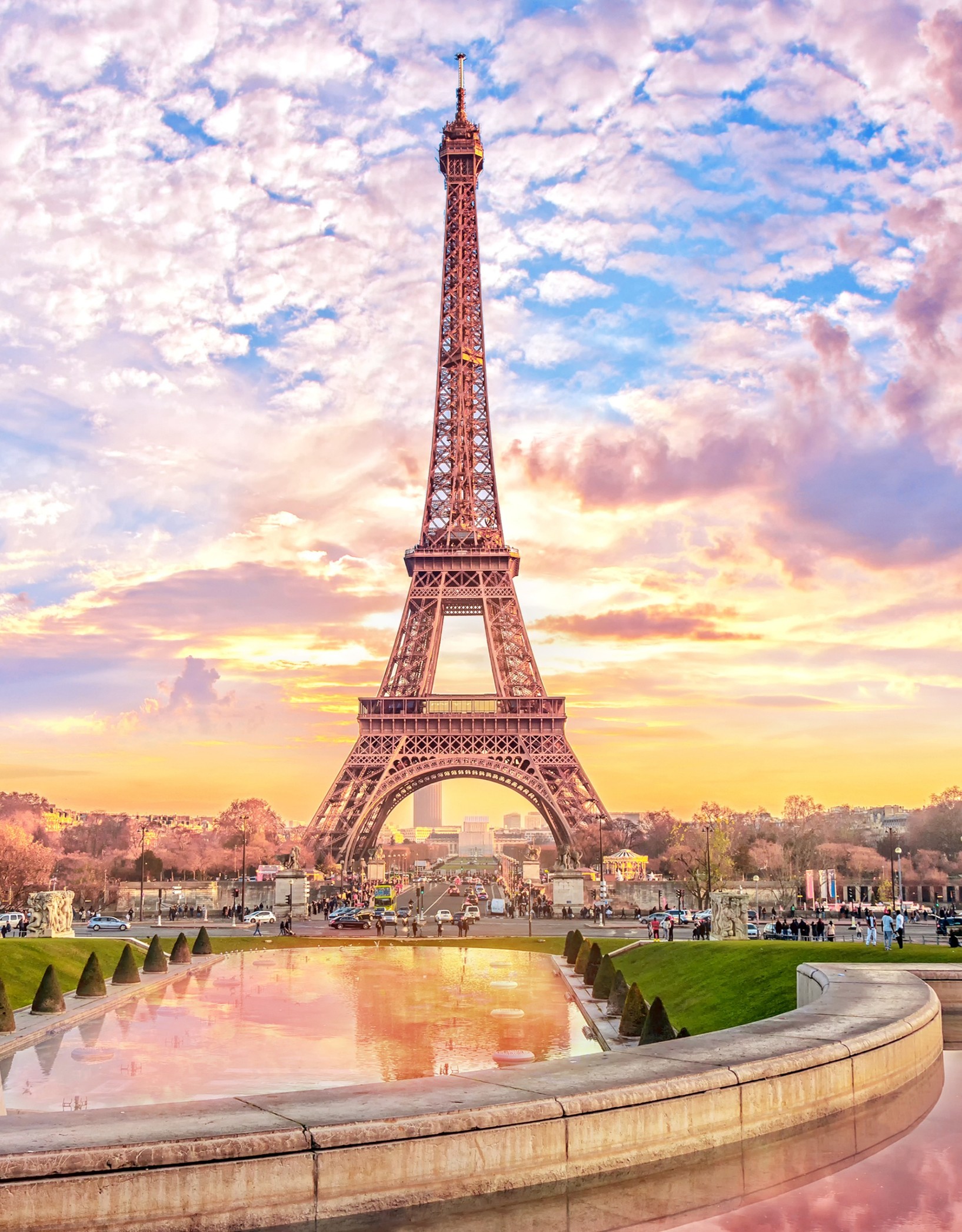 The Eiffel Tower at sunset with a reflecting pool in the foreground.