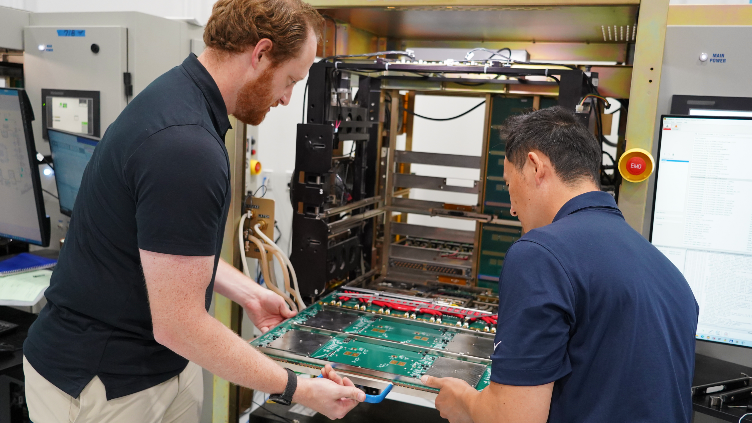 Two technicians working together to install a circuit board into an industrial computer chassis.