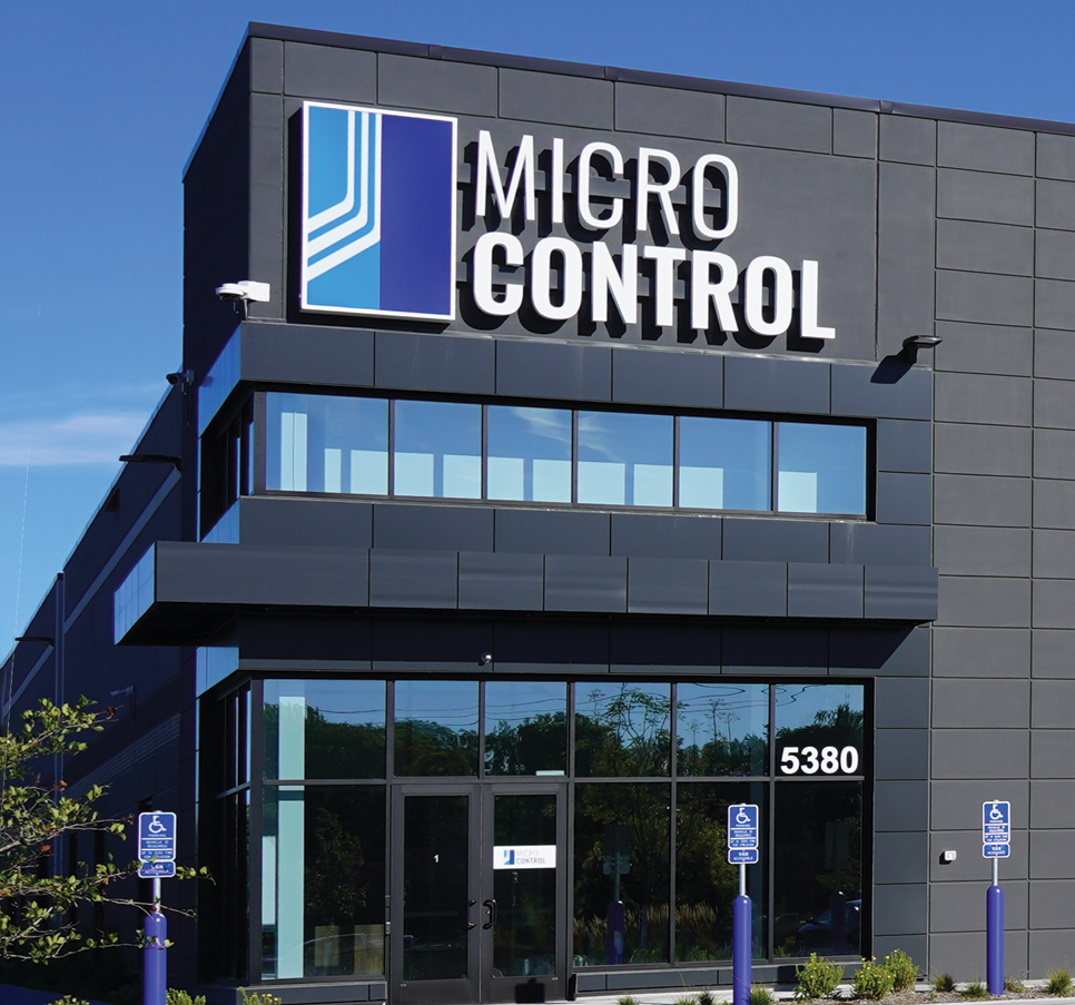 Exterior view of the Micro Control company building with a large sign above the entrance and the number 5380 displayed on the glass.