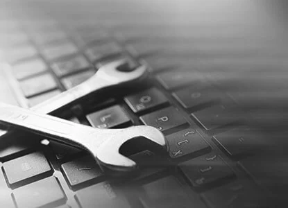 Two metal wrenches lying across a laptop keyboard.